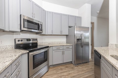 A kitchen with stainless steel appliances and white cabinets.