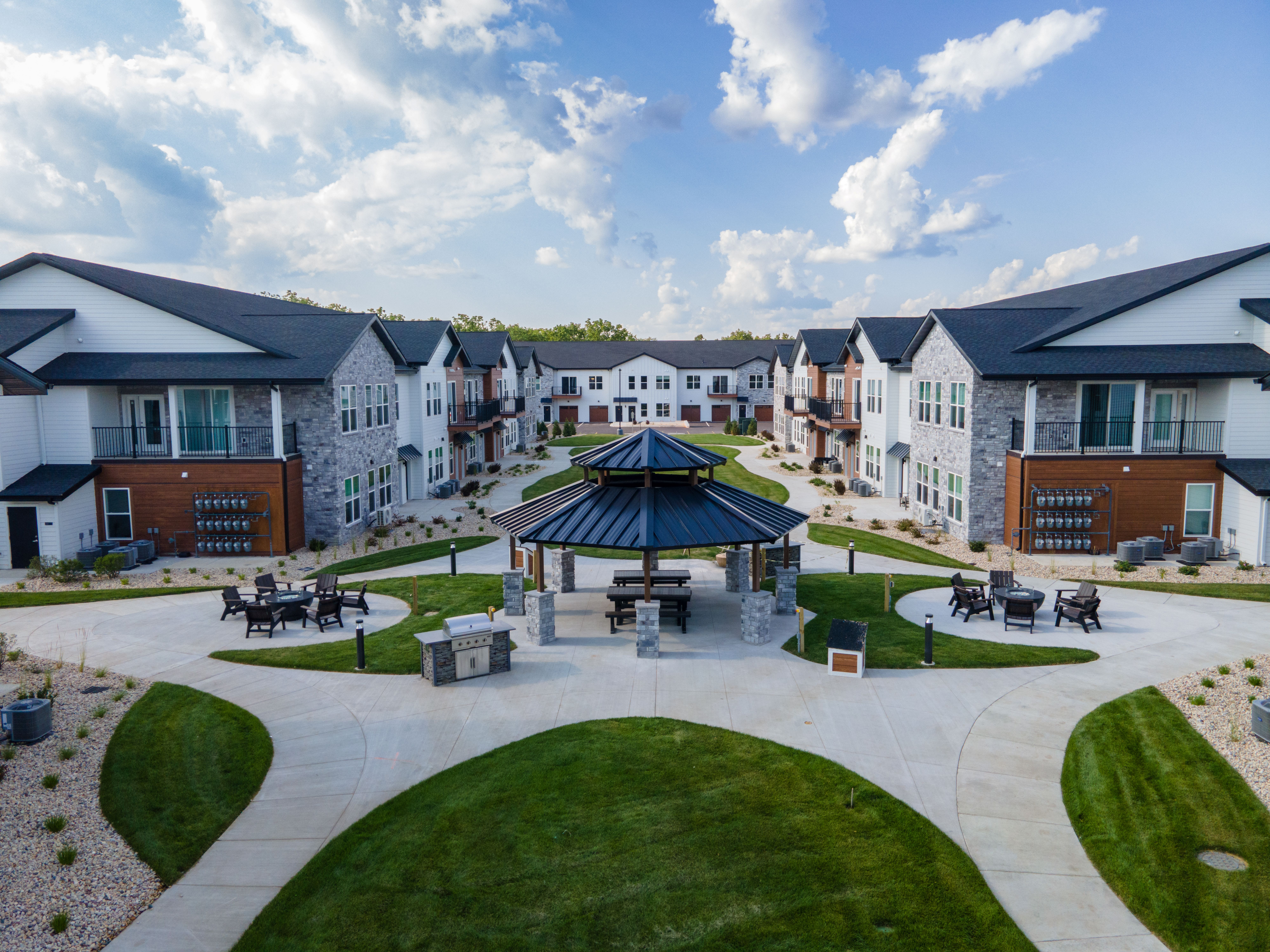 A gazebo is surrounded by a grassy area in the middle of a housing development.