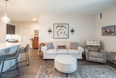A living room with a white couch, a grey armchair, and a white ottoman.