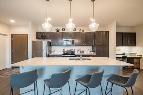 A modern kitchen with a bar and chairs.