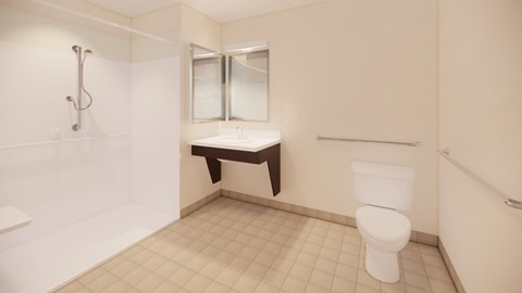 A white toilet sits in a bathroom with a white tub and shower.