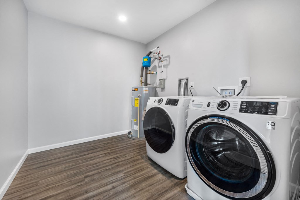 two washing machines in a laundry room with white walls and wood floors