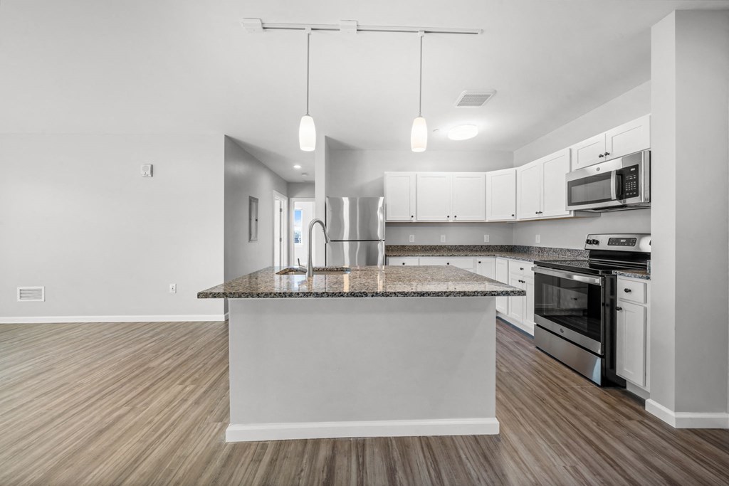 an empty kitchen with a granite counter top and stainless steel appliances