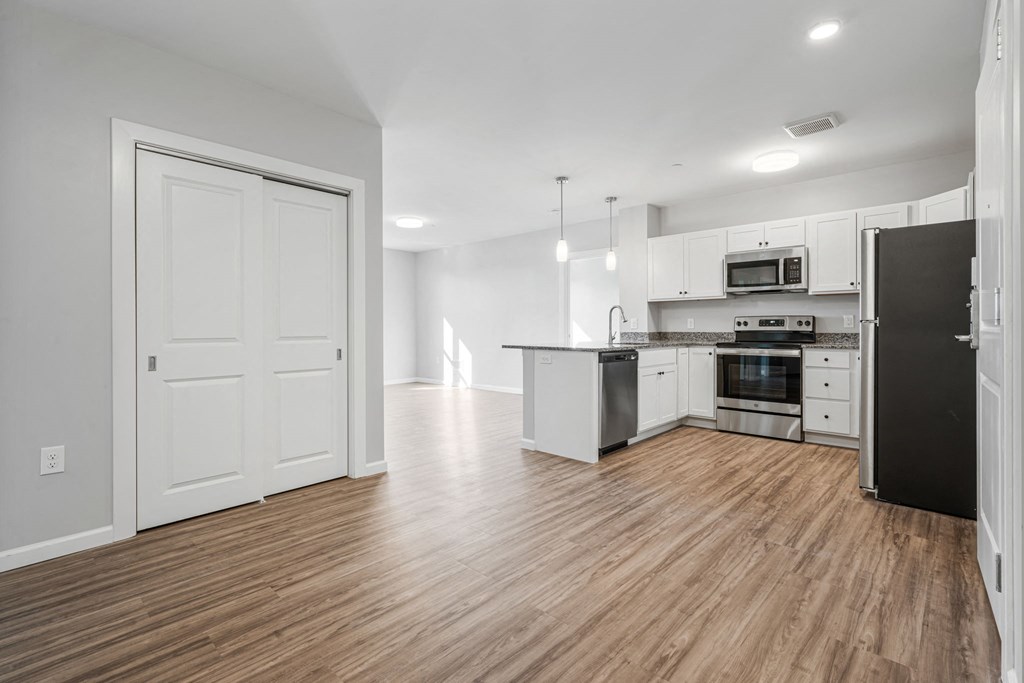 an empty kitchen and living room with white walls and wood floors