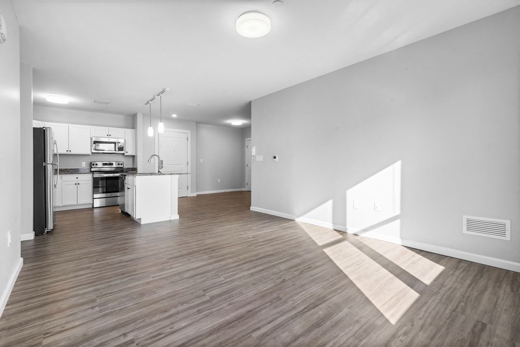 a renovated living room and kitchen with white walls and wood floors