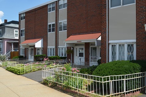 A brick building with a white fence in front.