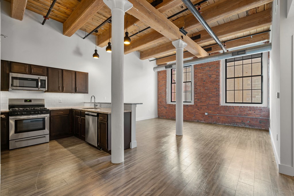 Open kitchen and living space with exposed beams and brick