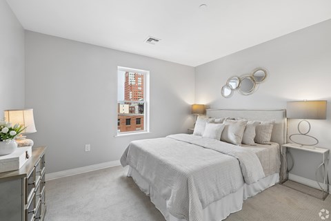 A bedroom with a large bed and a window overlooking a building.