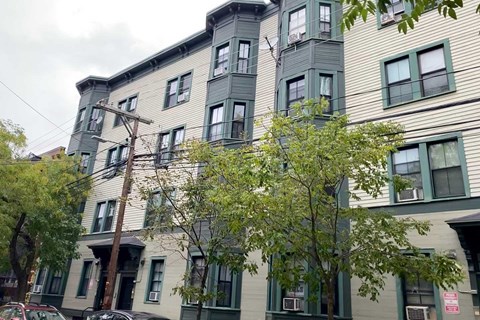A multi-story building with a mix of green and beige siding.