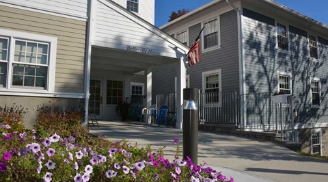 A building with a sign that says "Intrepid House" is surrounded by flowers.