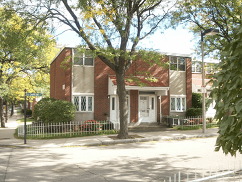 A red brick house with a white fence in front.