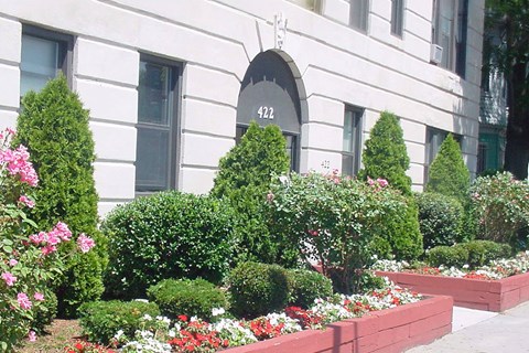A white building with a garden in front.