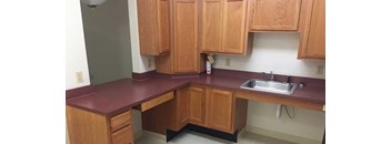 A kitchen with wooden cabinets and a maroon countertop.