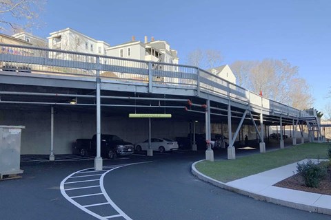 A parking garage with a white car and a black truck parked inside.