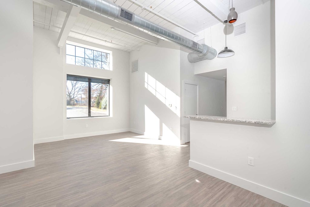 Open living space with sunlight, high ceilings and exposed loft features.