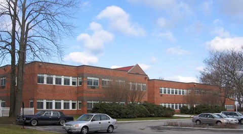 A red brick building with cars parked in front.