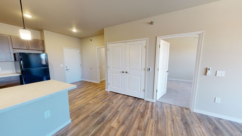 an open living room and kitchen with a black refrigerator and wood flooring