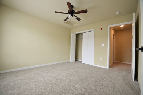 A room with a ceiling fan and carpeted floor.