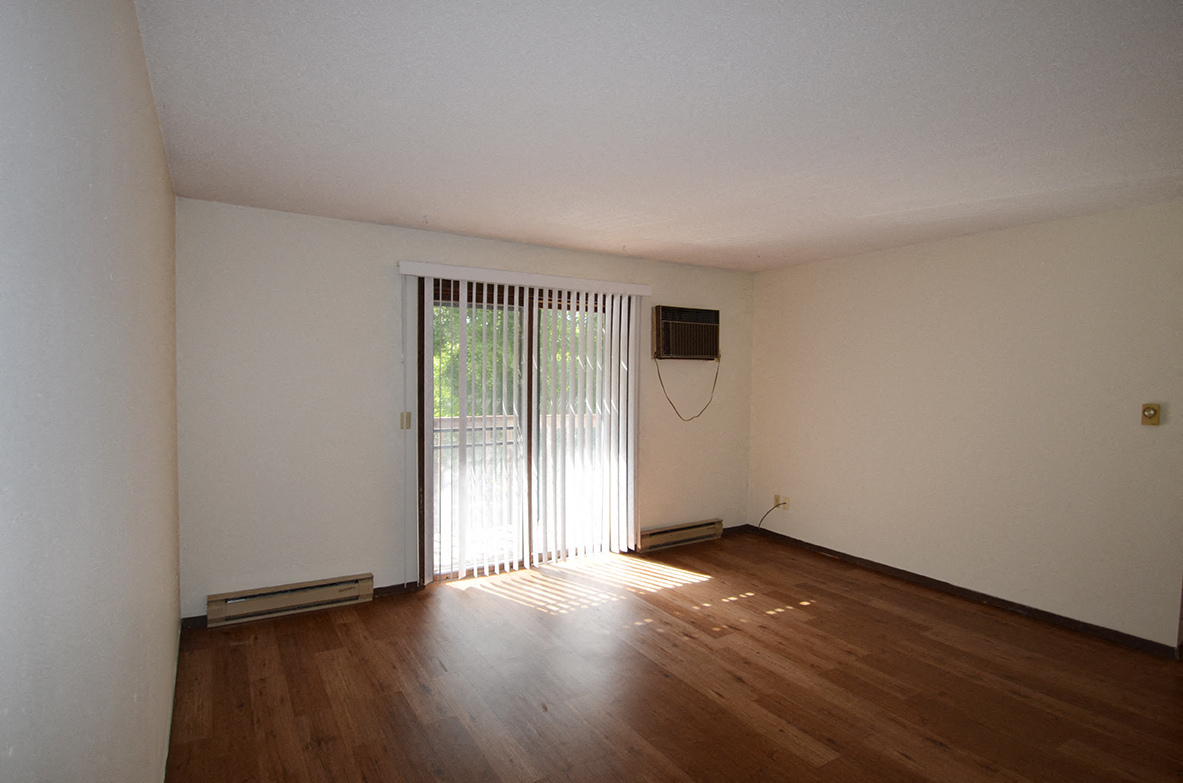 A room with wooden floors and a window with blinds.