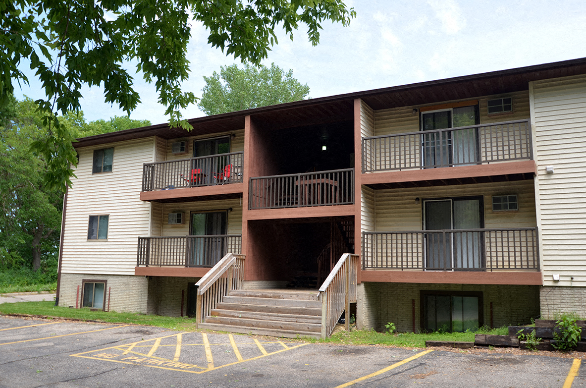 A two-story apartment building with a parking lot in front.