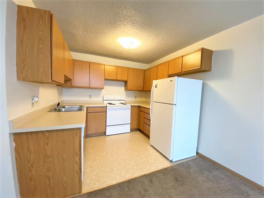 a kitchen with white appliances and wooden cabinets