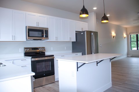 A kitchen with white cabinets and a black fridge.