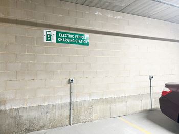 an electric vehicle charging station sign on the wall of a parking garage