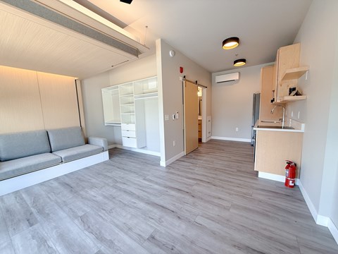 A living room with a grey sofa and a grey floor.