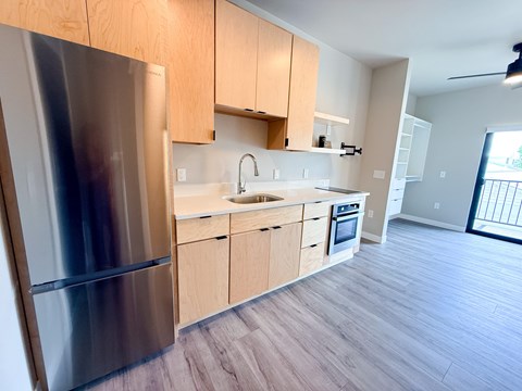 A modern kitchen with wooden cabinets and a stainless steel refrigerator.