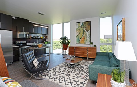 A modern living room with a black leather chair and a green sofa.
