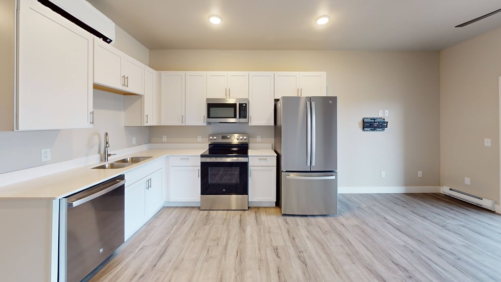 A kitchen with white cabinets and a wooden floor.