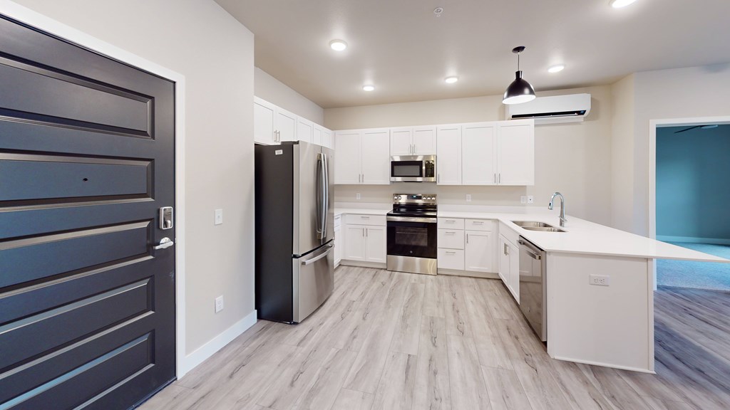 A modern kitchen with white cabinets and a black refrigerator.