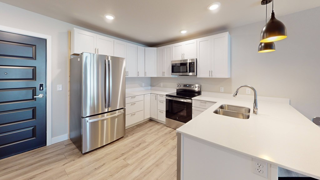 A modern kitchen with a stainless steel refrigerator and a sink.