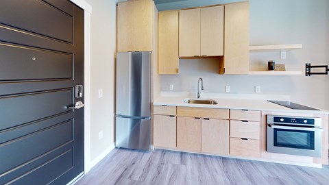A modern kitchen with wooden cabinets and a stainless steel refrigerator.