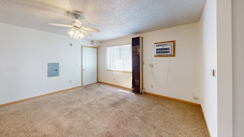 an empty living room with a ceiling fan and a window