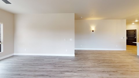 A spacious room with wooden flooring and white walls.