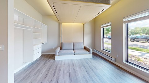 A spacious room with a white couch and a window overlooking a parking lot.