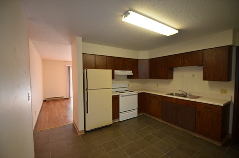 A kitchen with a white refrigerator, a white stove, and brown cabinets.