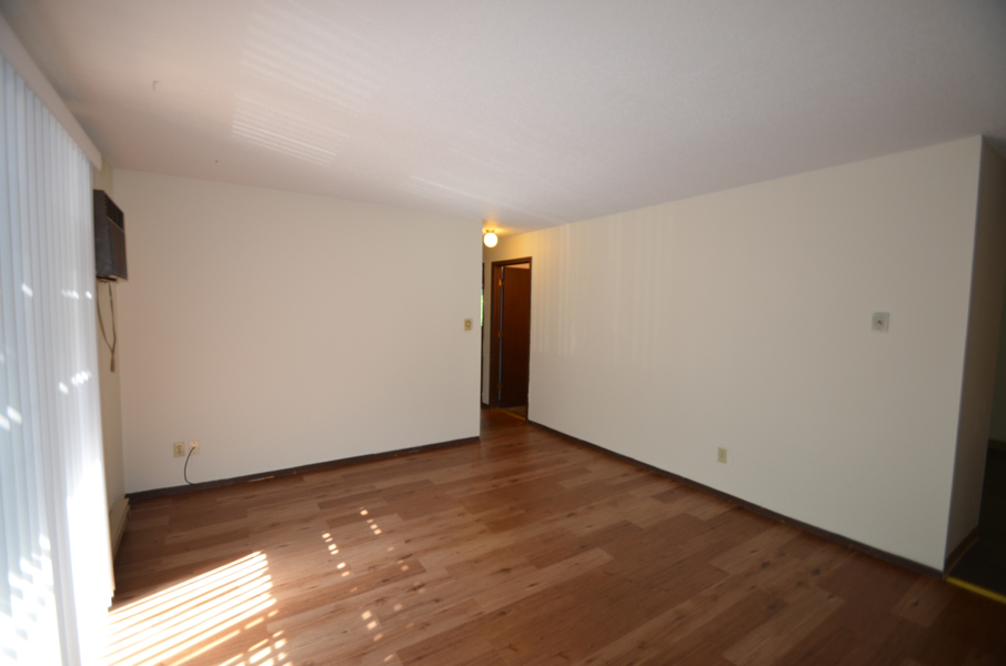 A room with wooden flooring and a door in the background.