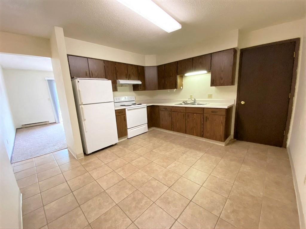 a kitchen with a white refrigerator and a sink