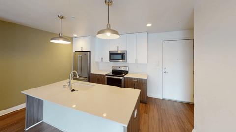 A kitchen with a white counter top and a microwave on the counter.