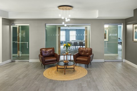 A living room with a brown leather chair and a glass table.