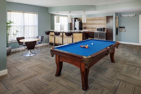 A pool table in a room with a bar and kitchen area.