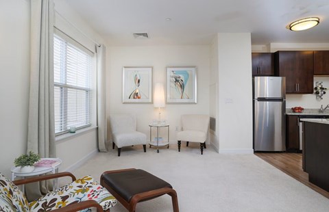 A living room with a couch, chair, ottoman, and a painting on the wall.