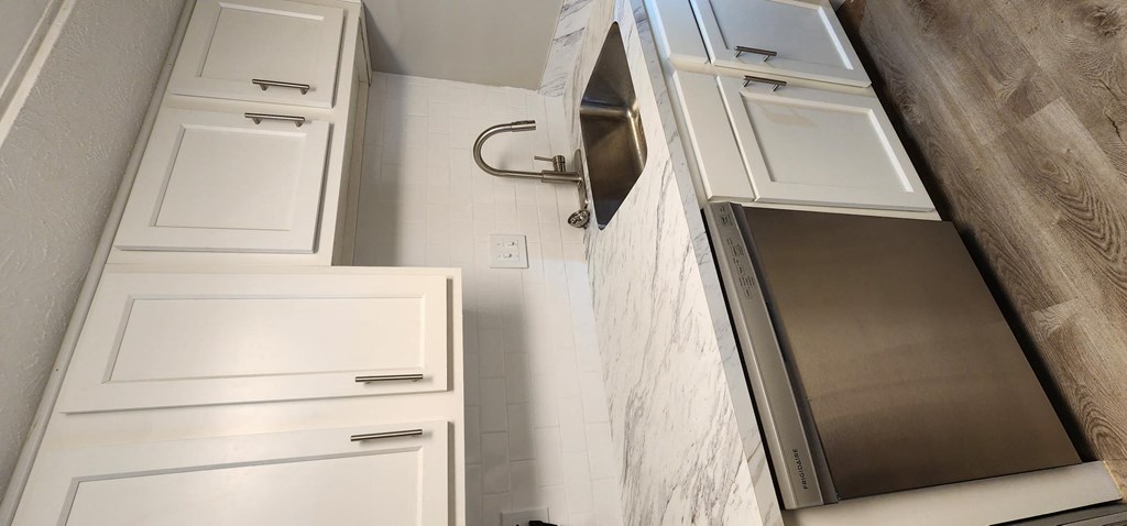 a small bathroom with white cabinets and a mirror