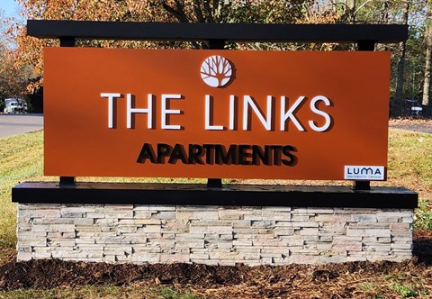 a sign for the links apartments is shown in front of a stone retaining wall