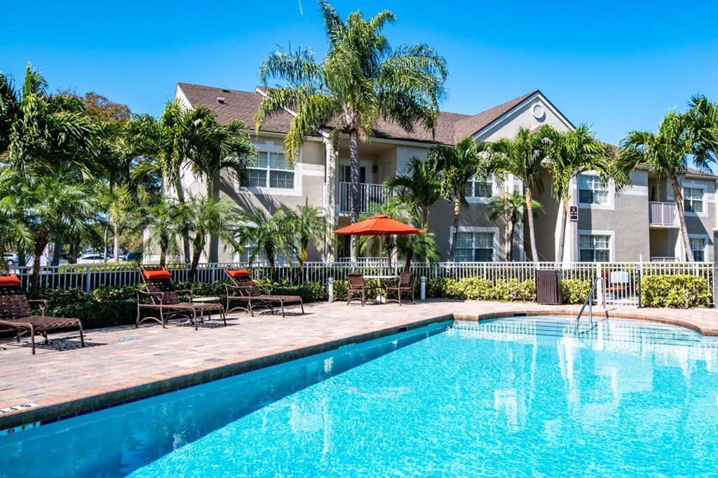 a large swimming pool in front of a building with palm trees