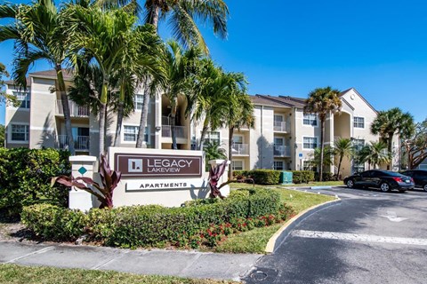 a building with palm trees and a sign in front of it