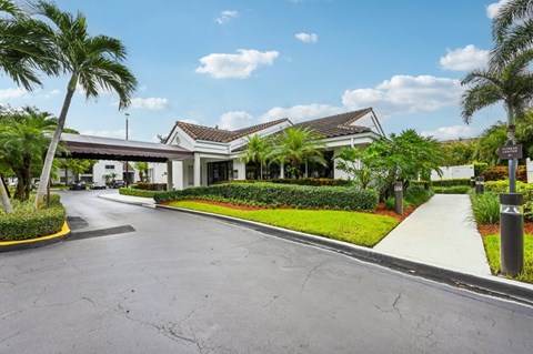 A road with a white building and palm trees on the side.