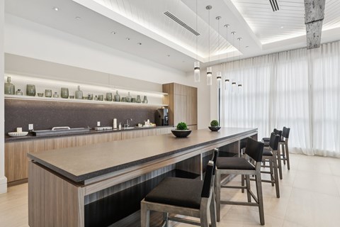 A modern kitchen with a long island and chairs.